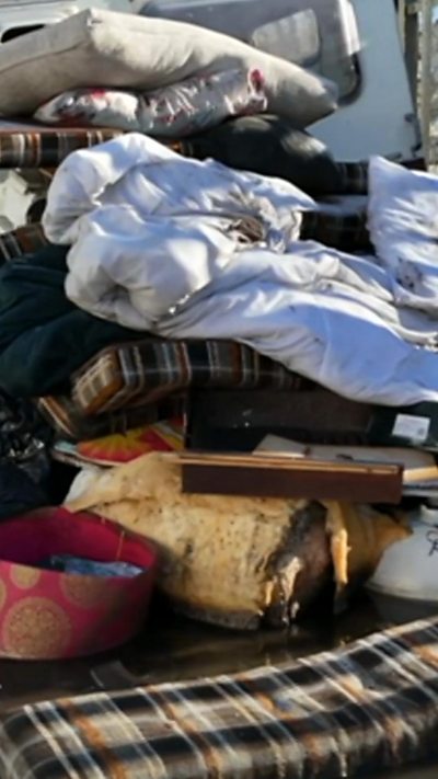 A pile of fly-tipped rubbish, including bedding, dumped in a street