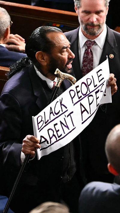 US Representative Al Green, Democratic from Texas, exits as he holds a sign.