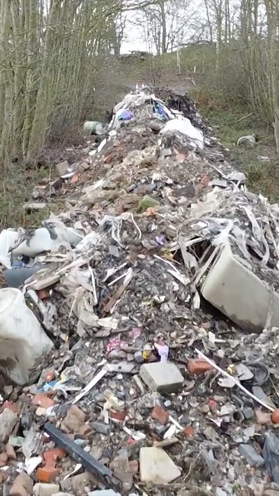 20m long pile of dumped waste near side of the road