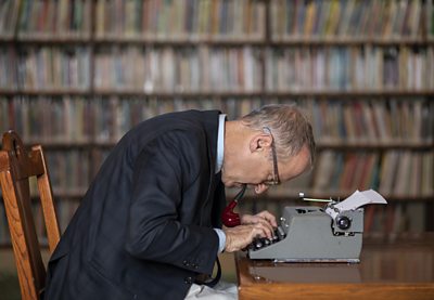 A man (David Sedaris) sits at a typewriter