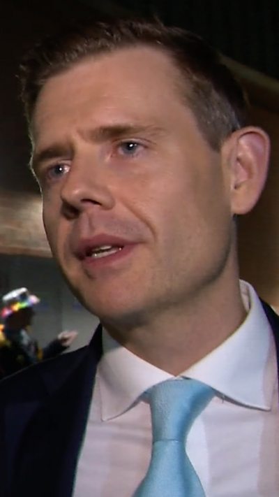 Man wearing suit and blue tie standing outside at night