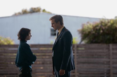 A young woman and a man confront each other in a garden.