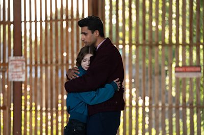A young woman and a man share a hug.