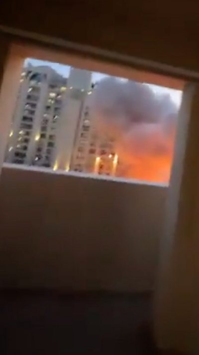 Large plumes of smoke and fire are seen from a balcony