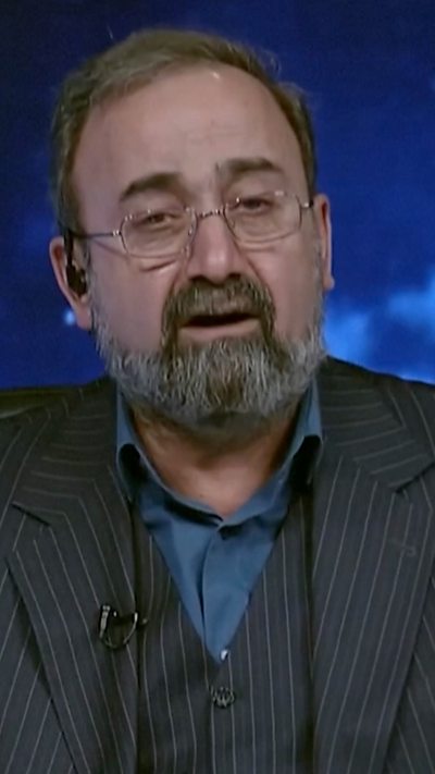 A news reporter is speaking to camera in a striped suit and blue background.