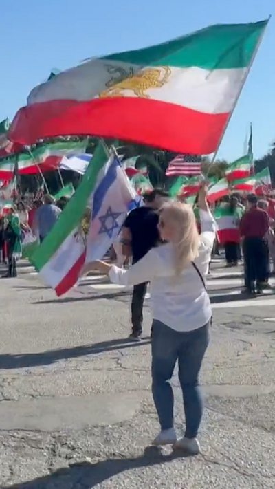 A woman holding an Iranian flag is seen dancing in the street