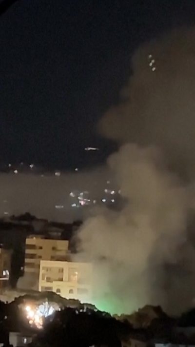 A night sky in Lebanon with smoke rising between high rise buildings