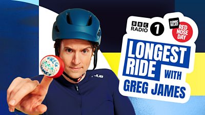 Photo of Greg James wearing a cycling helmet and holding a red nose. 