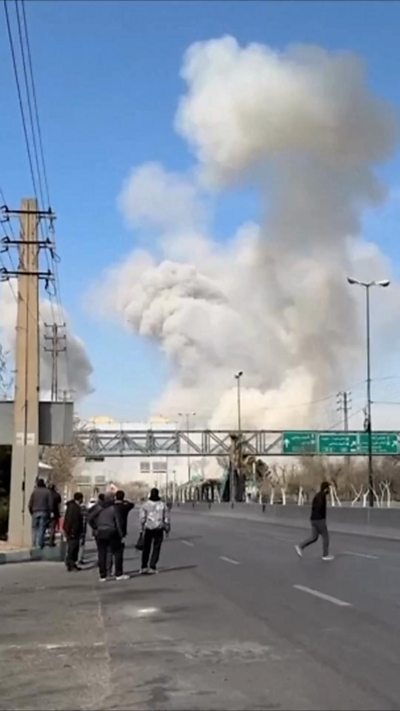 People standing up on highway, a plume of white smoke in the background