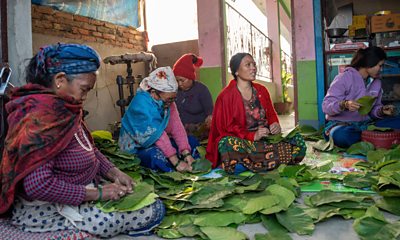 Women in village in Nepal making plates made from leaves