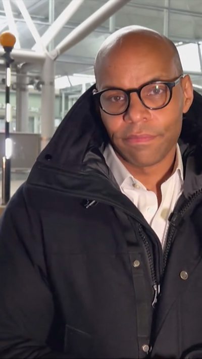 Greg McKenzie standing outside Stansted Airport in a jacket