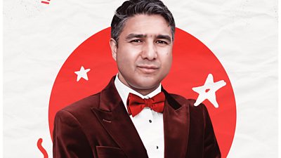 Photo of Nick Mohammed smiling in front of branding for Red Nose Day 2026. 