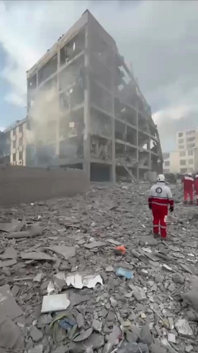 Debris surrounding destroyed building with emergency teams seen on the ground
