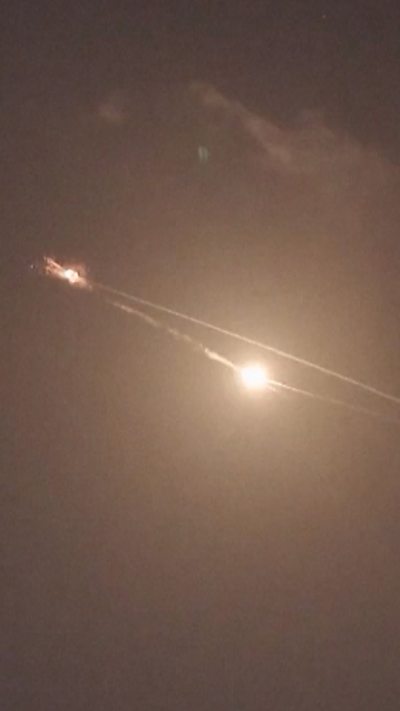 A bright yellow circle and streaks are seen in the night sky as missiles are intercepted.