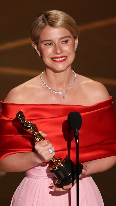 Jessie Buckley is seen holding an Oscars award.