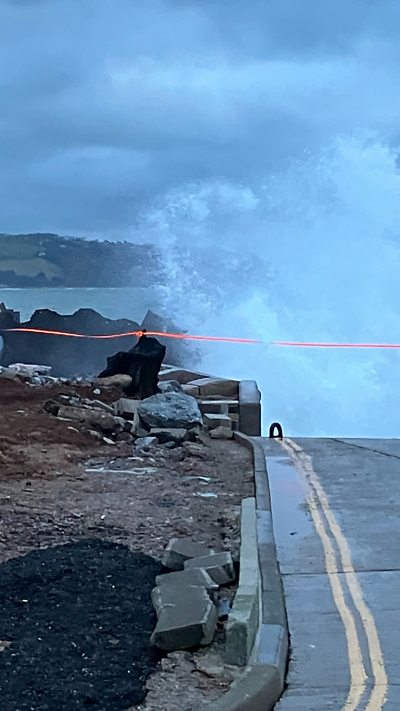 A wave crashing in against the damaged seawall in Torcross.