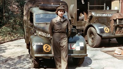 Photo of Queen Elizabeth II leaning against a military vehicle. 