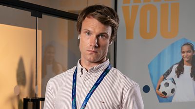 A man in a striped shirt stares to camera