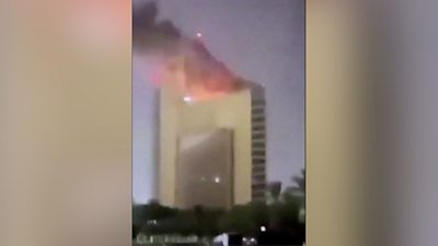 A skyscraper building on fire in the night.