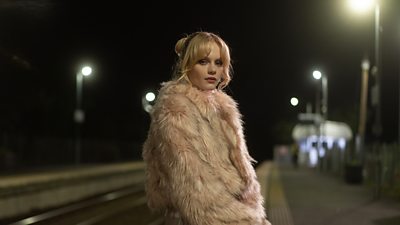 Photo of Emma Laird in character as Shannon. Stood on a station platform. 