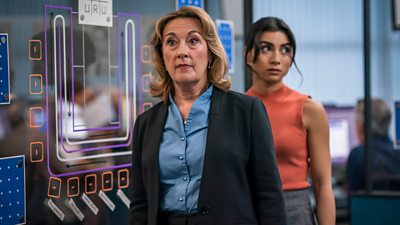 Dorothy Atkinson and Rumi Sutton in character as DCS Carol Shaw and DC Caitlin Sullivan respectively. The pair stand in an office.