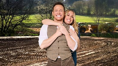 Composite image of a man and woman (Joe Swash and Stacey Solomon) standing together smiling and hugging, set against the backdrop of a large hole that's been dug in a field