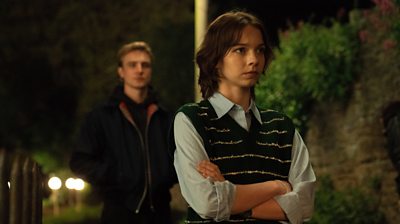 Emma Myers playing Pip stood in a blue short and green vest, with Henry Ashton playing Max stood in the background