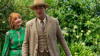 Lesley Manville as Susan Ryeland and Tim McMullan as Atticus Pünd. The pair walk outside on a sunny day. 