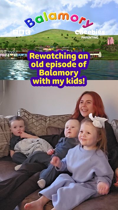 A mother sits on a sofa with her three young children watching Balamory.