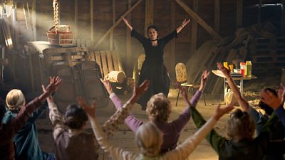 A group of people stood in a dusty barn with the arms held to the sky