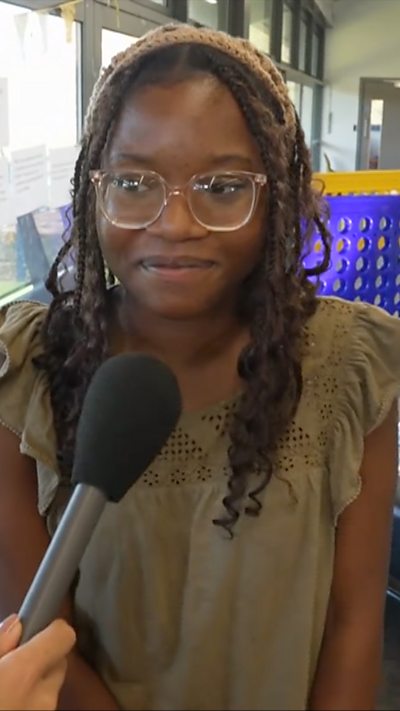 Student standing in front of foosball table speaking to reporter