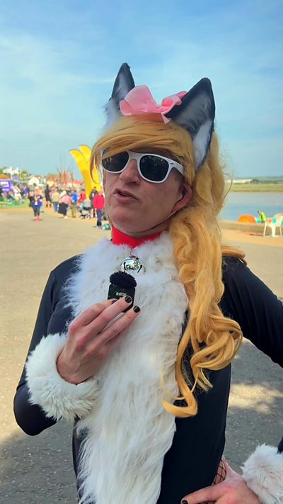 Man dresses as a cat with a blond wig on bank of river