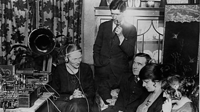 Listeners gathered round a radio set or listening on headphones, c. 1926