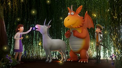 Zog the orange dragon standing next to two doctors as they help a white unicorn