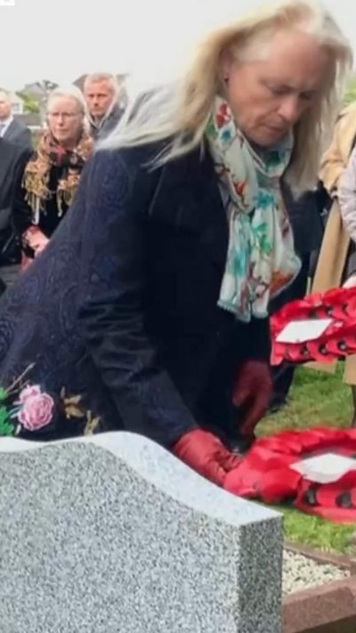 A woman laying a wreath of poppies on a grave.