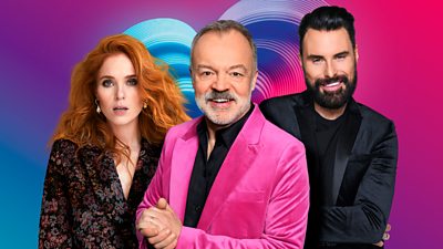 Angela, Graham and Rylan standing in front of a multi coloured background
