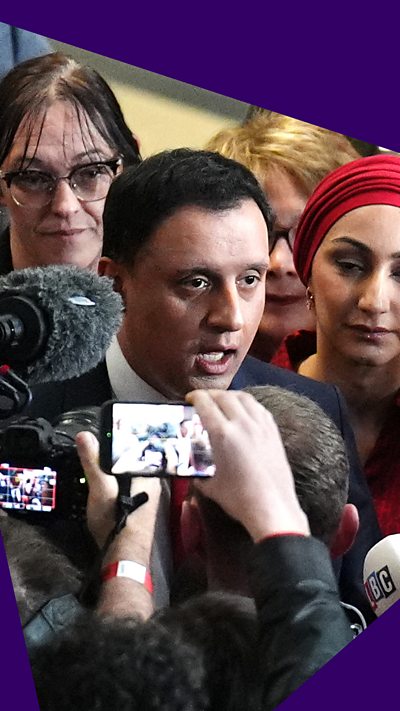 Anas Sarwar surrounded by journalists answering questions