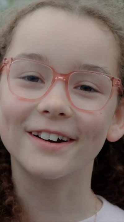 A close-up shot of a girl wearing glasses as she speaks to the camera