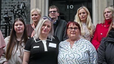 A group of people stood outside No 10 Downing Street. 