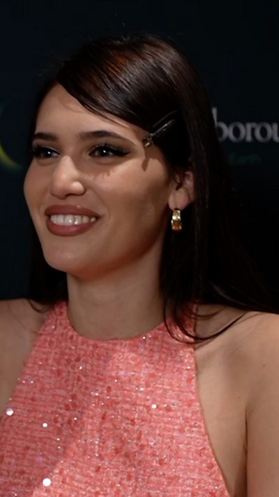 A smiling Sienna Spiro in a pink dress being interviewed at the Royal Albert Hall.