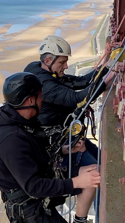 Two men with hard hats on abseiling off Blackpool Tower