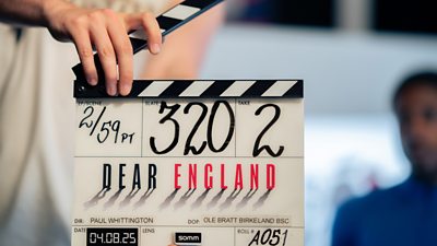 A clapper board with the Dear England logo written across it