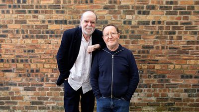 Phil Differ and Jonathan Watson standing against a brick wall and smiling towards the camera 