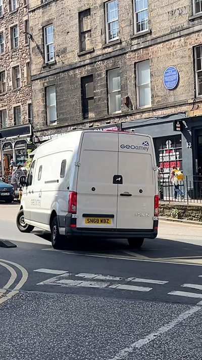 A white van is turning the corner on an Edinburgh street.
