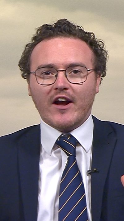 Jack Fenwick wears a blue suit and tie