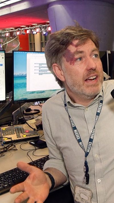 Robert Cuffe speaks to a reporter as he sits at his computer with a BBC lanyard on