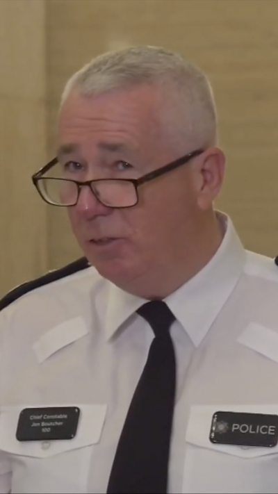 PSNI Chief Constable in a white shirt and black tie.