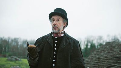 Steve Coogan in an old suit holding a potato