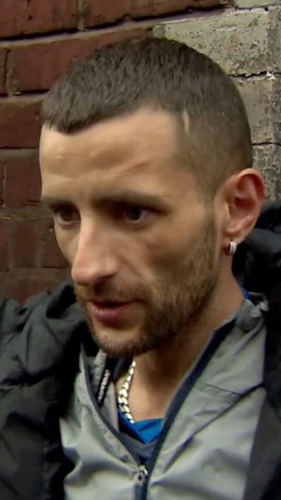 Close-up of resident being interviewed in front of his burnt house