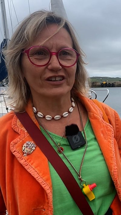Woman wearing an orange jacket with an overcast sky in the background